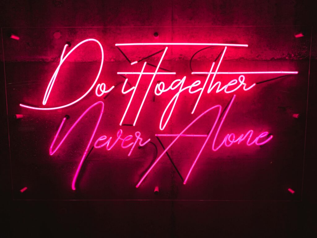 Neonschriftzug, rot auf schwarz: do it together, never alone